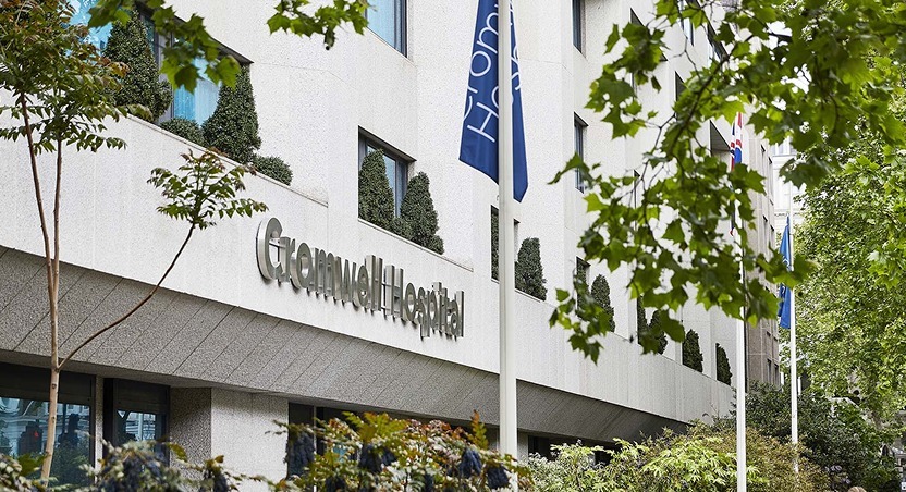 A modern hospital building with the sign Grosvenor Hospital on its exterior, several flags on flagpoles, and trees with green foliage in the foreground—a place known for treating Dupuytren’s contracture symptoms and related conditions.