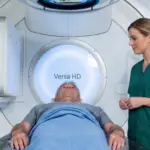 Patient on a Versa HD linear accelerator beside a radiographer, for Dupuytren's radiotherapy