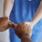 Two people holding hands, one in blue scrubs, suggesting care or support—an image reflecting compassion for those seeking Dupuytrens contracture treatment UK or dealing with the causes of Dupuytrens disease.