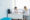 A doctor and a patient are sitting across from each other at a desk in a bright, modern medical office, discussing Dupuytren’s contracture symptoms. The doctor is facing the patient, who is seated on a white chair.