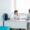 A doctor and a patient are sitting across from each other at a desk in a bright, modern medical office, discussing Dupuytren’s contracture symptoms. The doctor is facing the patient, who is seated on a white chair.