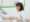 A female healthcare professional wearing a white coat and gloves smiles while holding a patient’s arm in a clinic, where medical equipment and a green-framed mirror are visible—highlighting care for Dupuytren’s contracture symptoms.