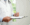 A doctor in a white coat holds a clipboard and pen, appearing to write notes about Dupuytren’s contracture disease. A stethoscope hangs around the neck. The background is bright and out of focus.