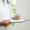 A doctor in a white coat holds a clipboard and pen, appearing to write notes about Dupuytren’s contracture disease. A stethoscope hangs around the neck. The background is bright and out of focus.