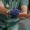 A healthcare professional wearing green scrubs and blue gloves gently holds a patient’s hand, offering comfort and support during a medical consultation about Dupuytren’s contracture symptoms.