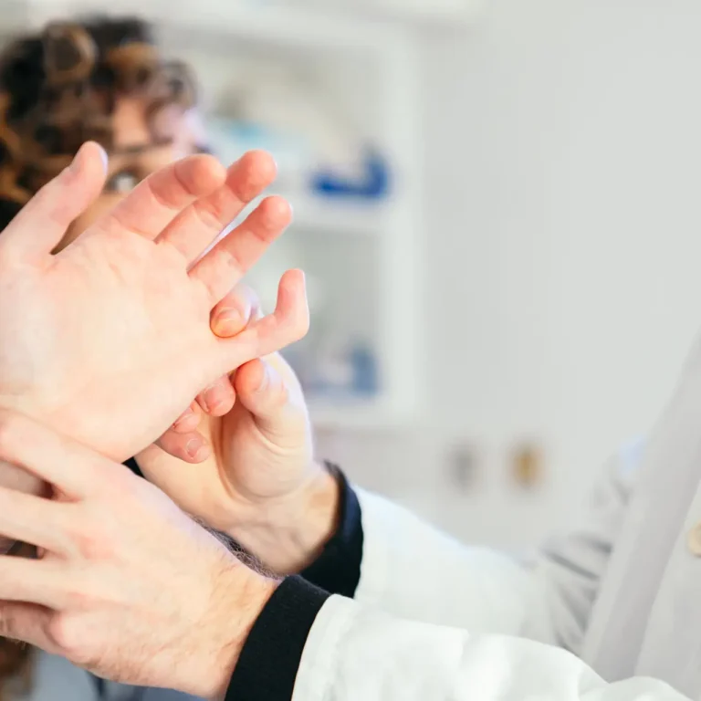 A physician and a nurse meticulously examine a patient's bent finger.