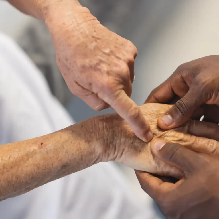 Midsection of african american male doctor examining hands of senior female caucasian patient. Hospital, work, medicine and healthcare.