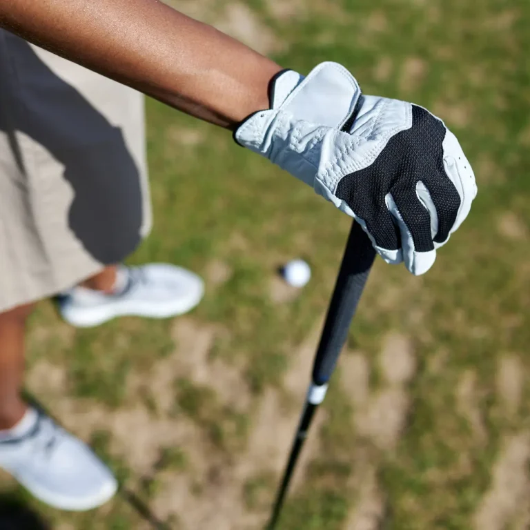 Top view closeup of gloved female hand holding golf club outdoors against grass, copy space
